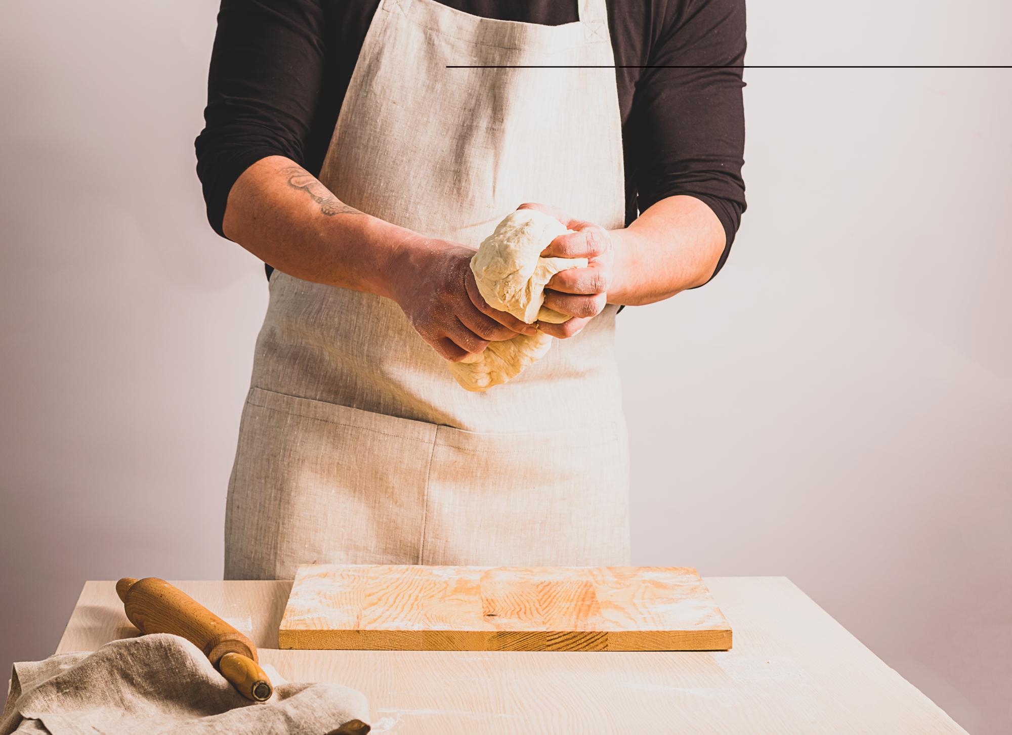 Chef shaping fresh pasta on wooden board
